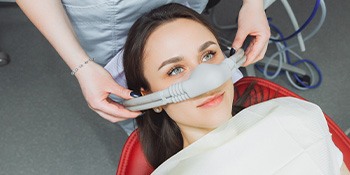 Hands of dentist on nitrous oxide mask over patient’s nose
