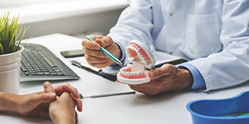 A dentist showing a patient a mouth mold while explaining where their dental implants will fit in Phillipsburg