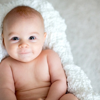 A happy baby laying on a towel