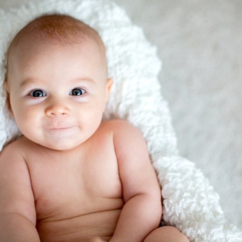 A happy baby laying on a towel