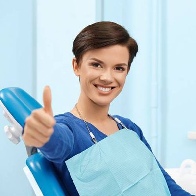 Woman in dental chair giving thumbs up