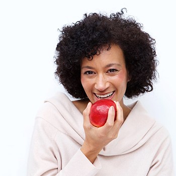 Woman with dental implants in Lehigh Valley eating an apple