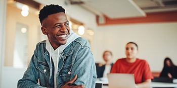 Teen in denim jacket smiling in classroom