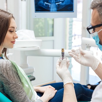 Dentist showing patient an implant model