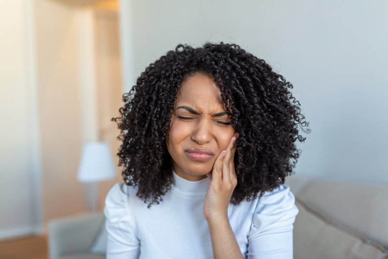 Woman holds cheek in pain