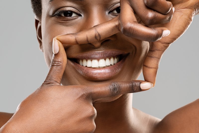 A woman framing her smile with her fingers after cosmetic dentistry treatments