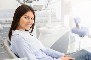 Female dental patient sitting in chair and smiling