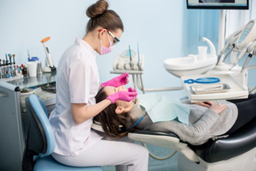 dentist putting dental filling on female patients’ tooth 