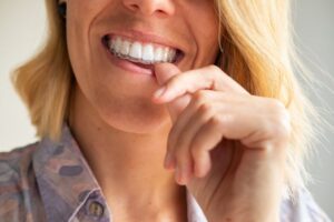 Woman smiling and putting on her clear aligners
